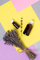 A bunch of dried lavender and oil in a bottle against a background of colorful blocks.