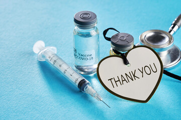 bottle of covid19 vaccine and syringe and gheart shape thank you tag