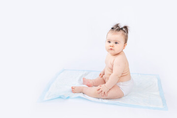 baby in diapers sitting on a disposable diaper on a white insulated background, space for text,...