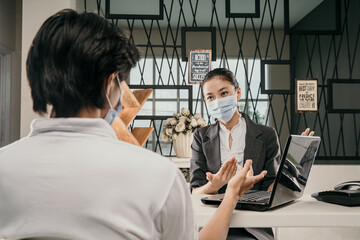 businesswoman present data in laptop to men and wearing health masks and keep social distance in...