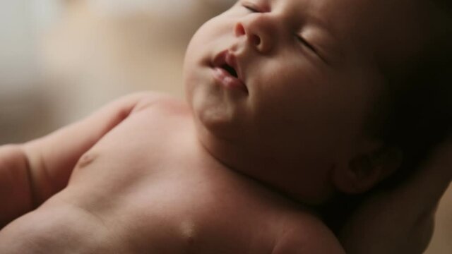 Cinematic video mother holds new born baby in her arms he sleeps and yawns, tenderness and care for the child. Maternity and motherhood concept.