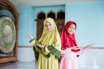 Two kid girl asian Muslim smiling showing something in mosques