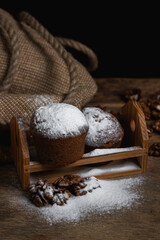 Cupcakes sprinkled with powdered sugar on a dark background. Confectionery on a black background. Walnut muffins