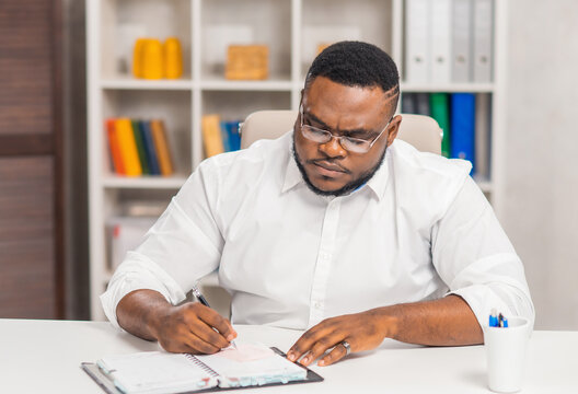 Freelance designer workplace at home office. Young African-American man works using a computer, graphics tablet and other devices. Remote job.