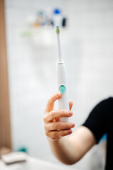 A female hand holds and shows an electronic toothbrush. Technology and dental health.