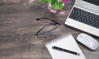 Office workspace. Laptop, mouse, notepad, pen, eyeglasses.