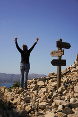 Woman with arms outstretched towards the sky, on top of a mountain