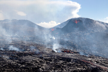 Steaming lava after a snowfall. Dramatic photo of a volcanic eruption at Fagradalsfjall, Iceland.