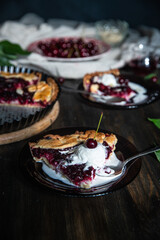 Piece of homemade cherry and custard pie with vanilla ice cream on glass plates on dark wooden table.