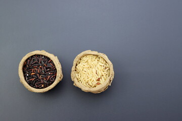 Black and brown rice in round paper bowls on a gray background.