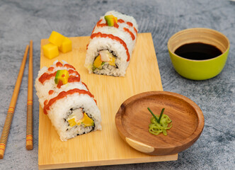 Rise sushi with avocado salmon mango in soy sauce in a wood plate 