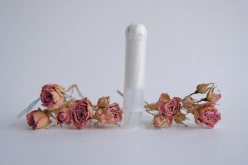 menopause concept. dried red rose lies on a woman tampon. dried rose and tampon represent withered female beauty and the cessation of monthly menstrual cycles (menopause)