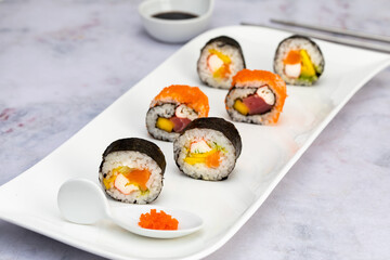 Sushi rolls with salmon, avocado and crab palm on a white plate with soy sauce