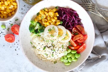 Rice salad with vegetables and sesame on light background. Top view with copy space. Healthy eating.