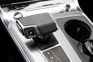 Automatic gear stick of a modern car. Modern car interior details. Close up view. Car inside. Automatic transmission lever shift. Black leather interior with stitching