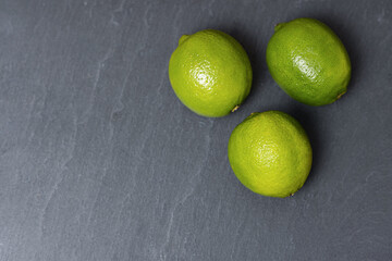 Fresh lime fruits on dark slate background