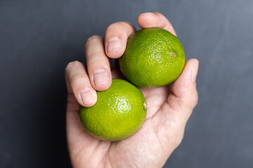 Man's hands grabbing two fresh limes