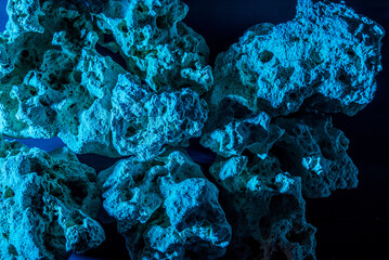 A pile of stones forming a cave, illuminated by an ominous blue light. Selective focus. Background, backstage, template for your creativity.