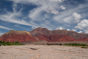 Desert canyon background. View of the arid sand and colorful mountains under a dramatic blue sky with beautiful clouds.