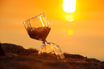 Obraz na płótnie Canvas Stylish hourglass on sand near river outdoors