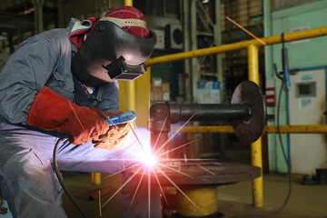 Welder is Welding process metal steel pipe Industrial worker with welding tool with sparks light weld and smokes in factory.