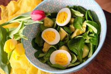 Gourmet Healthy Salad with Mâche, Avocado, and Egg, Decorated with a Yellow Tulip