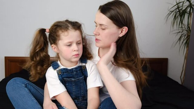 Close up of caring worried mother hugs and talks sad little daughter, giving support and comfort, loving caucasian young mom foster parent consoling small kid being bullied sitting on bed at home