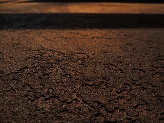 Textured background with shadows and light from the sun. Dark background. Desktop background. Black, gray, and yellow. Venetian plaster.
