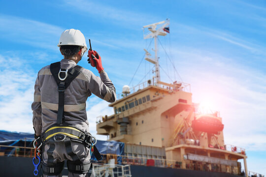 Workers with hand holding walkie talkie, communication radio in shipyard for ship repair or maintenance on floating dry dock yard