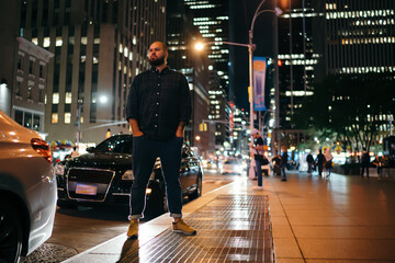 Cool stylish man standing on pavement of night city
