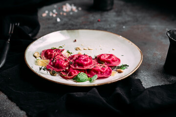 Beetroot ravioli with cheese on a white plate. Red ravioli