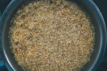 Pot cooking quinoa grains viewed from above, faded colors and film grain added.