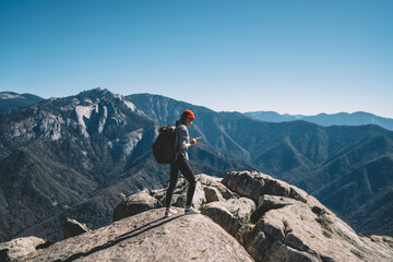 Traveler standing on mountain top and scrolling phone