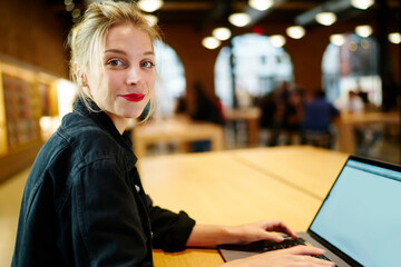 Cheerful woman using laptop in cafe