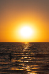 Fototapeta premium Fisherman catches fish in the sea at sunrise or sunset