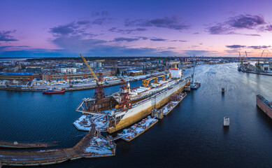 Ship repair and maintenance docks in beautiful sunset colors. Giant cargo vessel being repaired at dockyard in Riga. 