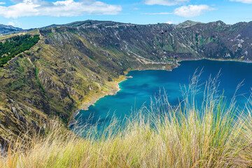 Andes grass with Quilotoa volcanic crater lagoon in background along the Quilotoa Loop hike, Quito region, Ecuador. Focus on grass.