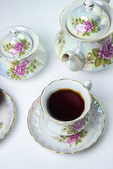 A cup of tea on a white tablecloth. Tea with muffins. Light breakfast. White tea set with flowers.