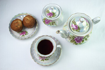Obraz na płótnie Canvas A cup of tea on a white tablecloth. Tea with muffins. Light breakfast. White tea set with flowers.