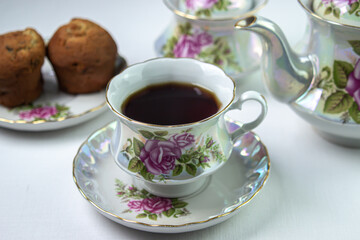 A cup of tea on a white tablecloth. Tea with muffins. Light breakfast. White tea set with flowers.