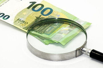 100 Euro Geldscheine unter der Lupe auf weißem Hintergrund