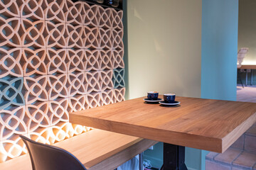 Two black cups of coffee served on a wooden table with empty chairs