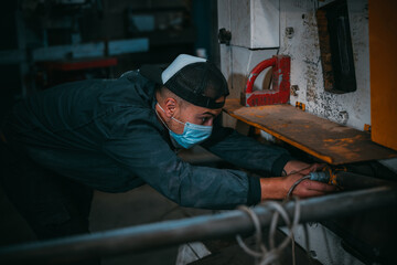 adult man in uniform works in an industry with machinery