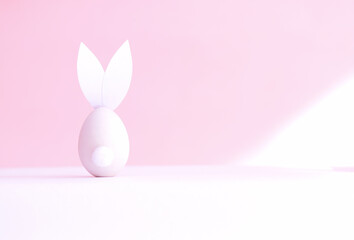 Easter egg in the form of a rabbit on a pink background, rear view