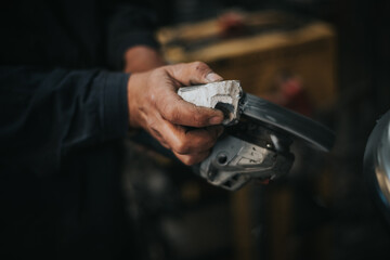 a hand of an adult man is seen working steel polishing in an industrial workshop