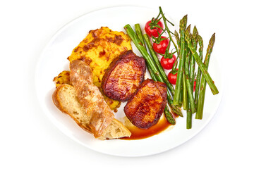 Grilled pork steaks with asparagus on a baked mashed potato, isolated on white background. High resolution image