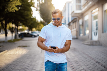 Young Man with mobile phone walking, background is blured city