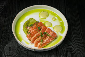 Sauteed salmon with basil sauce on a white round plate
