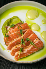Sauteed salmon with basil sauce on a white round plate

