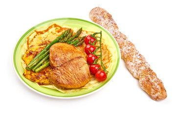 Roasted juicy pork steaks with asparagus on a baked mashed potato, isolated on white background. High resolution image